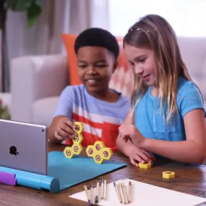 Play Shifu Plugo Link pedagogiskt spel med barn som bygger med gula pusselblock bredvid en surfplatta