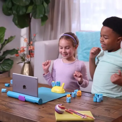 Plugo Count play system with blue play mat, tablet in holder, yellow snail module and blue number blocks, used by two children.