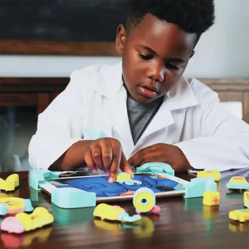 PlayShifu Tacto Doctor på tablet med turkise rammer og farverige lægedele; barn i hvid kittel, der leger og peger på bordet.